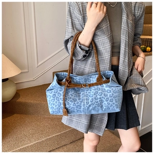 Dettaglio della borsa tote in tela con stampa leopardata e manici in pelle marrone