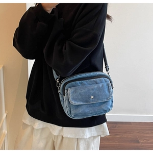 Detail of adjustable black nylon strap on a minimalist blue denim crossbody bag
