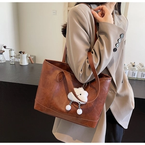 Brown vintage tote bag with cloud plush charm shown in a minimalist cafe setting
