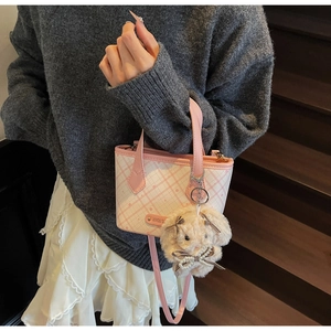 Detail of pink checkerboard tote bag with cute plush bunny charm and logo plaque