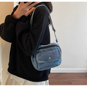 Detail shot of the blue denim crossbody bag featuring a magnetic flap front pocket and strap