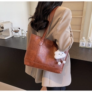 Retro brown leather tote bag with cloud pendant shown on model in a cafe setting