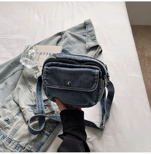 Close-up of blue denim crossbody bag with flap pocket and adjustable strap