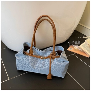 Détail du cabas léopard bleu clair avec lanières en cuir marron et boucle métallique chic