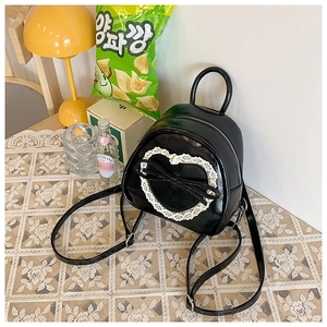 Vue détaillée d'un sac à dos noir brillant avec dentelle en cœur et n'ud élégant