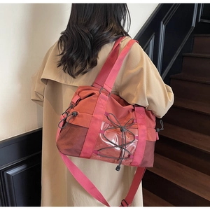 Detail of coral travel tote featuring breathable mesh side and adjustable shoulder strap