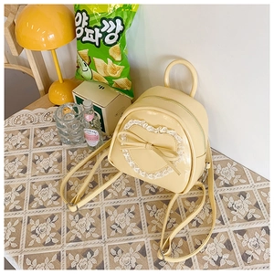 Détail du mini sac à dos en similicuir crème avec dentelle cœur et nœud élégant