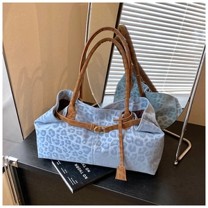 Détail du sac cabas imprimé léopard bleu avec poignées en similicuir marron et pendentif