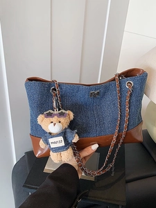Large denim tote bag with brown leather trim and bear pendant shown from a front angle