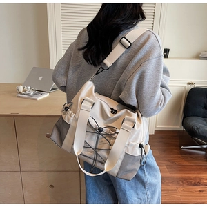 Détail du sac de voyage blanc cassé avec poches latérales en maille et cordons tactiques