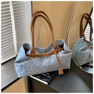 Détail d'un sac cabas léopard avec anses en cuir marron et boucle décorative dorée