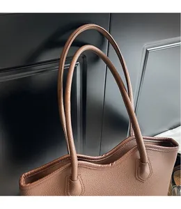 Gros plan d'un cabas en cuir grainé marron avec coutures renforcées et doubles fines anses