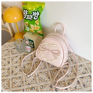 Détail de cœur en dentelle rose et nœud sur un mini sac à dos en similicuir
