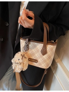 Checkerboard tote bag with brown handles and a plush rabbit charm shown on model
