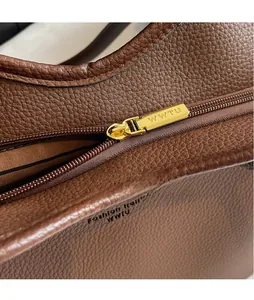 Vue détaillée du cuir grainé et de la fermeture éclair dorée sur le sac cabas marron