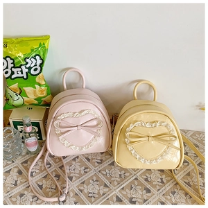 Détail de mini sacs à dos doux en rose et jaune avec dentelle coeur et nœuds en cuir