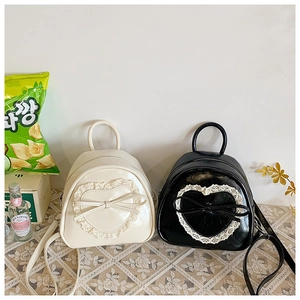 Vue détaillée des mini sacs à dos avec cœur en dentelle en crème et noir brillant