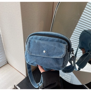Detail shot of light blue washed denim crossbody bag featuring a silver button closure