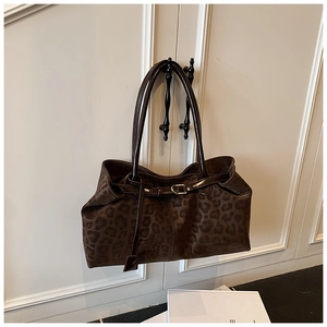Détail du grand sac cabas imprimé léopard avec anses en cuir sur un meuble blanc