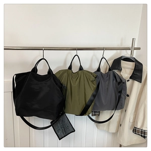 Three waterproof nylon tote bags in black, green, and gray displayed with a beige coat