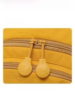 Détail d'un sac à dos jaune montrant la fermeture éclair double et le tissu imperméable