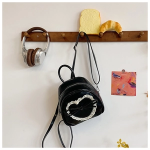 Détail d'un mini sac à dos en cuir PU noir avec dentelle en cœur et un nœud
