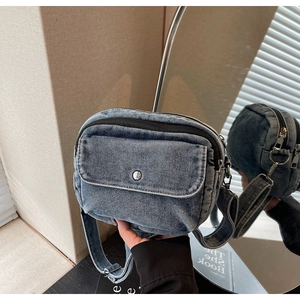 Close-up of vintage light blue washed denim crossbody bag with silver snap button detail
