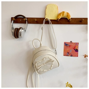 Détail du mini sac à dos crème avec patch cœur en dentelle et petit nœud délicat