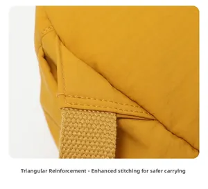 Gros plan sur la couture triangulaire renforcée des bretelles d'un sac à dos jaune