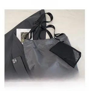Detail of dark grey nylon tote bag with mesh organizer pouch and wide shoulder strap