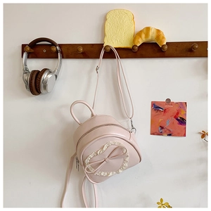 Détail du sac en cuir PU rose avec dentelle cœur et nœud sur cintre en bois