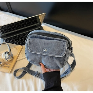 Close-up of blue denim crossbody bag with metal buckle in a campus study setting