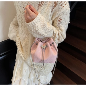 Sac seau rose avec cordon, papillon argenté et perles porté sur robe blanche