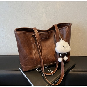 Detail of vintage brown tote bag texture with brand logo and plush cloud charm