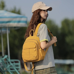Détail d'un sac à dos en nylon jaune avec poches multicouches porté par un modèle