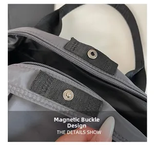 Detail shot of the magnetic closure on a gray nylon tote with black woven shoulder strap