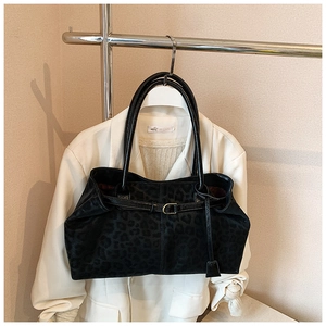 Détail du sac cabas noir à motif léopard porté sur un blazer blanc élégant
