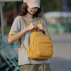 Détails d'un sac à dos de voyage en nylon jaune avec plusieurs compartiments zippés