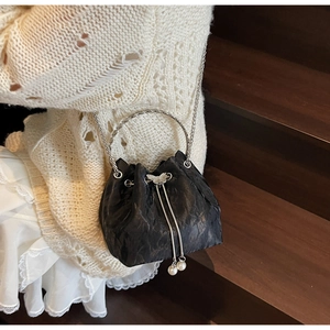 Détail du sac seau noir plissé avec poignée ronde argentée et perles blanches