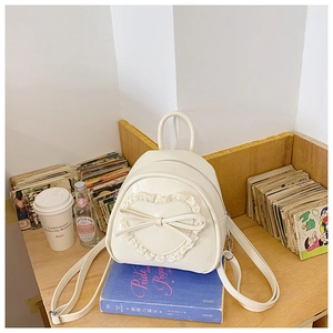 Détail du sac à dos crème avec dentelle en cœur et nœud en cuir sur tissu PU lisse