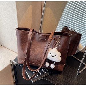 Macro shot of dark brown retro leather tote bag with cloud charm and embossed logo