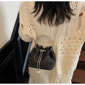 Modèle portant un sac seau noir avec papillon argenté et détails de perles fines
