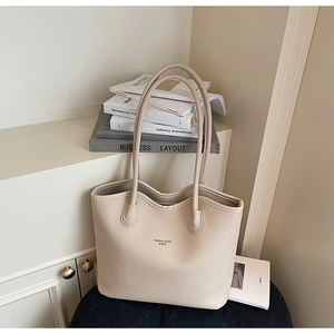Détail de la texture cuir grainé et du logo de la marque sur ce grand sac cabas beige
