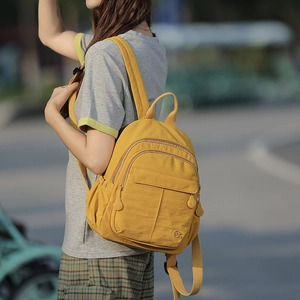 Détail du sac à dos en nylon jaune avec plusieurs poches et fermeture éclair griffée
