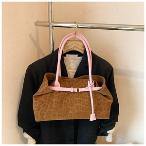 Détail d'un sac cabas léopard avec anses roses contrastées et boucle dorée élégante