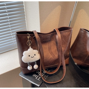 Brown vintage faux leather tote bag with a white plush cloud charm and logo detail