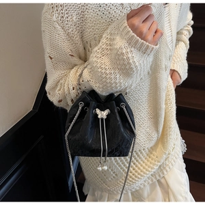 Détail du sac seau noir à cordon avec boucle papillon argentée et breloques perles