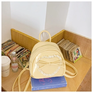 Détail d'un sac à dos crème en cuir PU avec dentelle en cœur et nœud sur une étagère