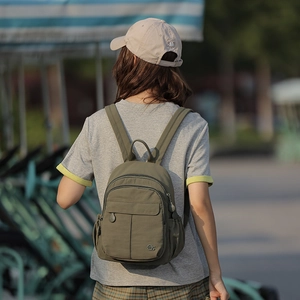 Détail d'un sac à dos en nylon vert olive avec plusieurs compartiments zippés et logo