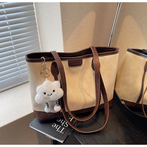Detail of a retro tote bag with textured faux leather and a cute plush cloud charm